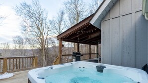Ein Whirlpool auf einer Holzterrasse mit einer überdachten Holzpergola.