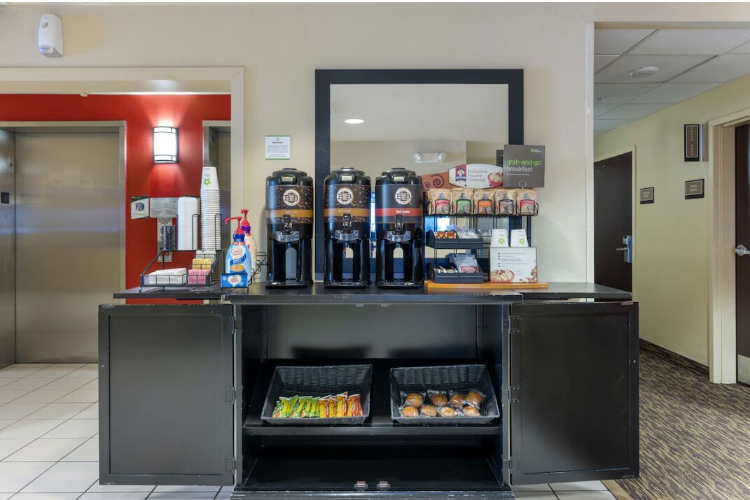 A hotel reception area with a coffee station, snack dispensers, and a counter with various items.