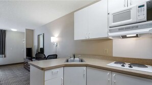 Une chambre d’hôtel compacte dotée d’une kitchenette, comprenant un four à micro-ondes, une cuisinière et un évier.