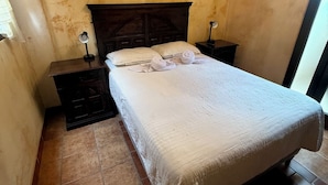 Un dormitorio con una cama de madera, dos mesitas de noche y una lámpara de pared.