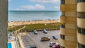 Vista de uma praia com um estacionamento e um edifício com varandas.