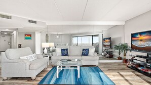 Un salon moderne avec un canapé gris, une table basse en verre et un tapis bleu.
