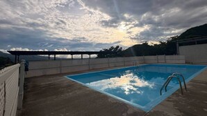 Suorakaiteen muotoinen uima-allas, jonka ympärillä on puinen terassi ja taustalla pergola.