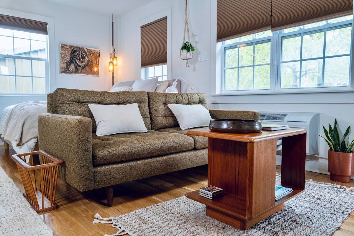 Un salon chaleureux avec un canapé marron, une table basse en bois et un tapis blanc.