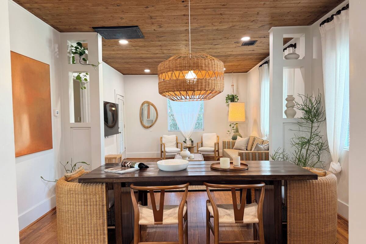 Un coin repas avec une table en bois, des chaises en osier et un luminaire suspendu.
