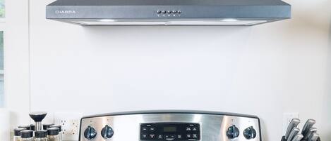 A kitchen with a black stove, a DIARRA hood, and a spice rack.
