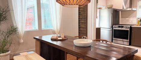 A modern kitchen with a wooden table, a woven pendant light, and a built-in oven.
