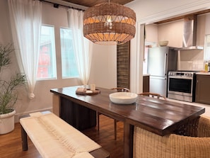 Una cocina moderna con una mesa de madera, una lámpara colgante de fibras tejidas y un horno empotrado.