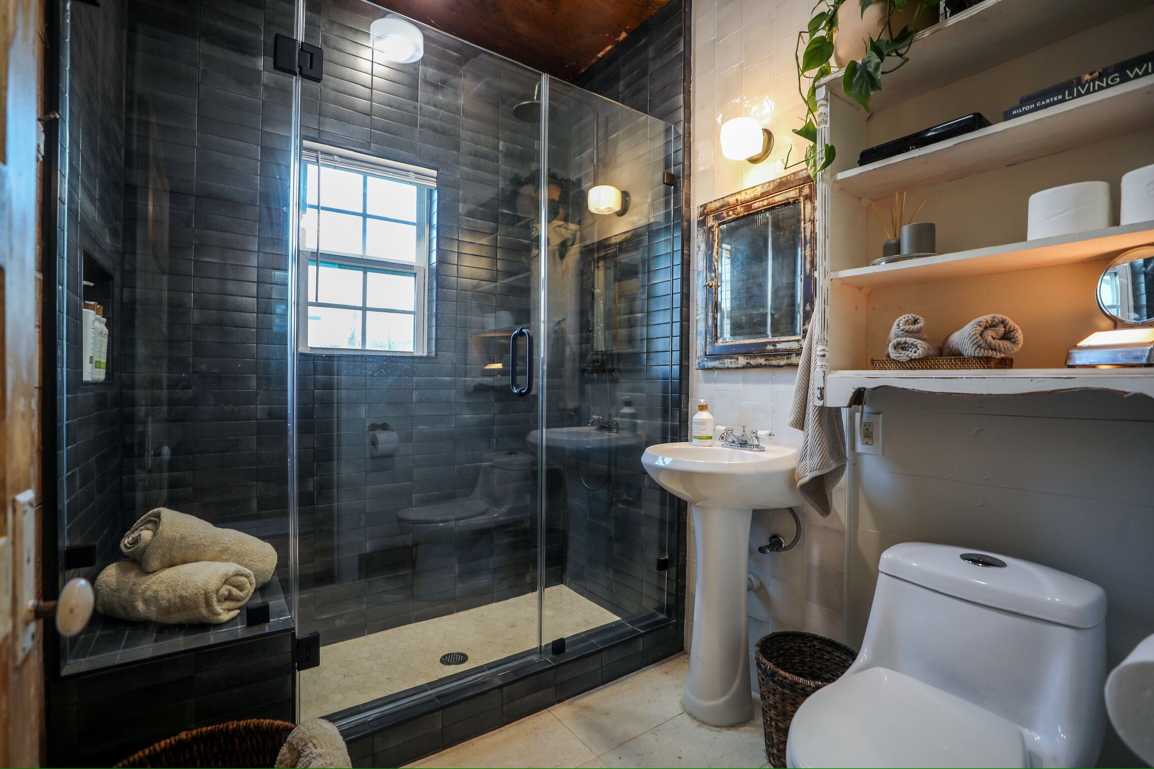 A modern bathroom with a glass-enclosed shower, a pedestal sink, and a toilet.