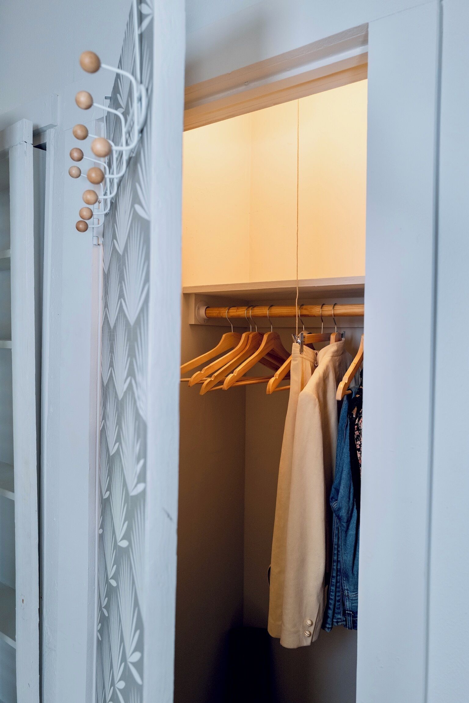Ein begehbarer Kleiderschrank mit Holzaufhängern und einer weißen Wandverkleidung.