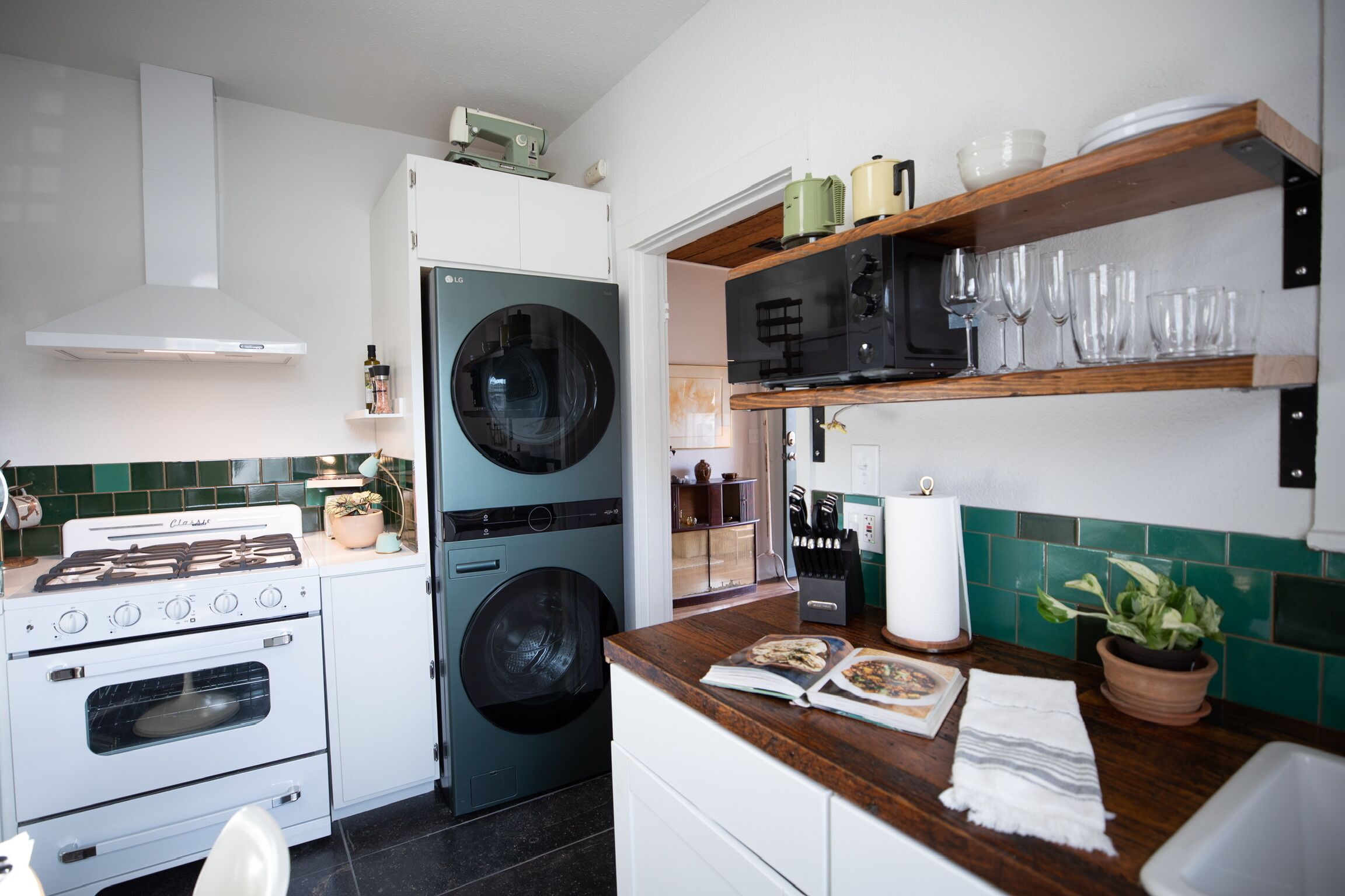 Eine kleine Küche mit Herd, Backofen, Waschmaschine und Holzböden mit Glaswaren.