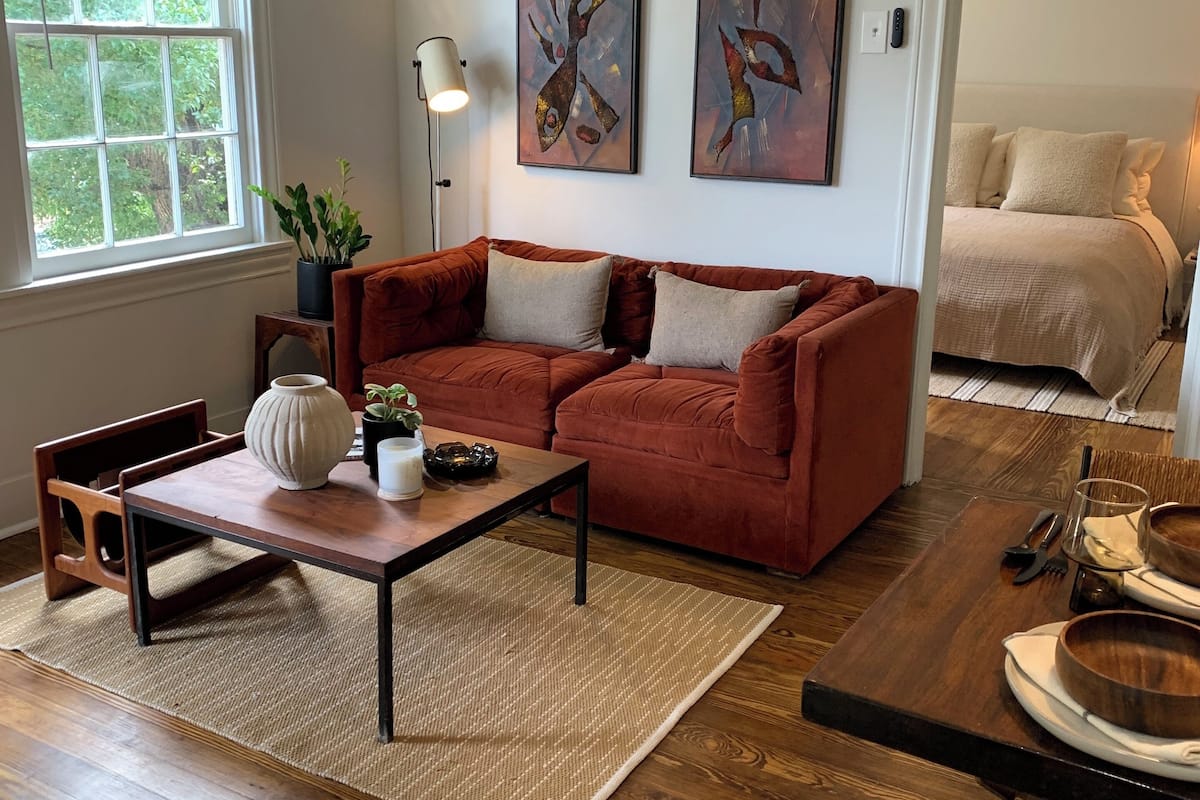 Un salon moderne avec un canapé rouge, une table basse en bois et des œuvres d’art abstraites accrochées au mur.