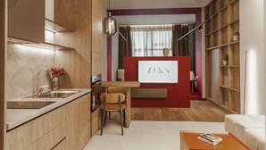 A modern kitchen with a wooden countertop, a sink, and a dining area with a table and chairs. There is a bookshelf and a decorative vase on the counter. - Zins Luxury Apartment 05 (Durrës)