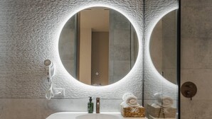 A modern bathroom with a round mirror, a white sink, and a towel basket. - Zins Luxury Apartment 05 (Durrës)