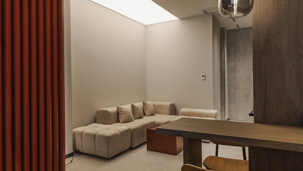 A modern living room with a sectional sofa, a wooden coffee table, and a skylight. - Zins Luxury Apartment 05 (Durrës)
