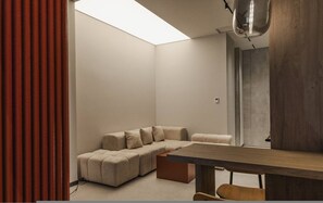 Un salon moderne avec un canapé d’angle, une table basse en bois et une lucarne.