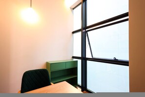 Una habitación con un escritorio, una silla y un mueble de almacenamiento verde.
