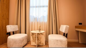 A room with two white cushioned chairs, a small marble table, and a window with sheer curtains. - Zins Luxury Room Vollga (Durrës)