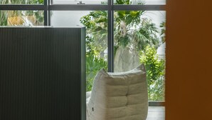 A room with a large window, a dark-colored partition, and a light-colored bean bag chair. - Zins Luxury Apartment 01 (Durrës)