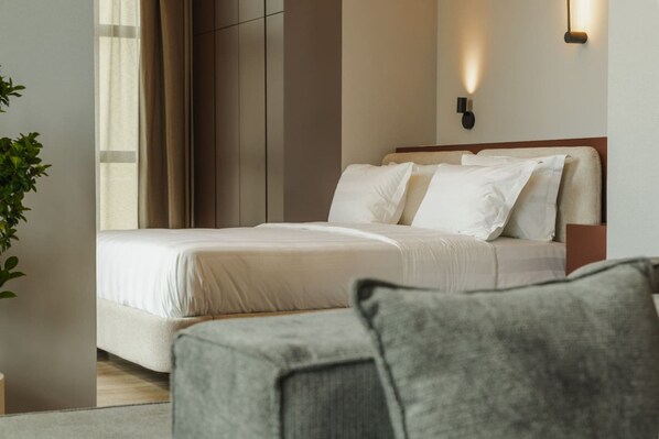 A modern hotel room with a large bed, a bedside table, a wall-mounted light, and a potted plant. - Zins Luxury Apartment 03 (Durrës)