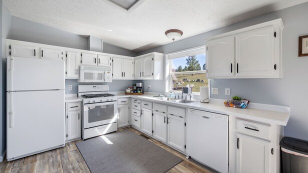 Una cocina moderna con armarios blancos, microondas integrado y ventana con vistas al exterior.