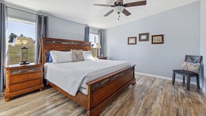 Un dormitorio con cama de madera, ventilador de techo y vistas al exterior.