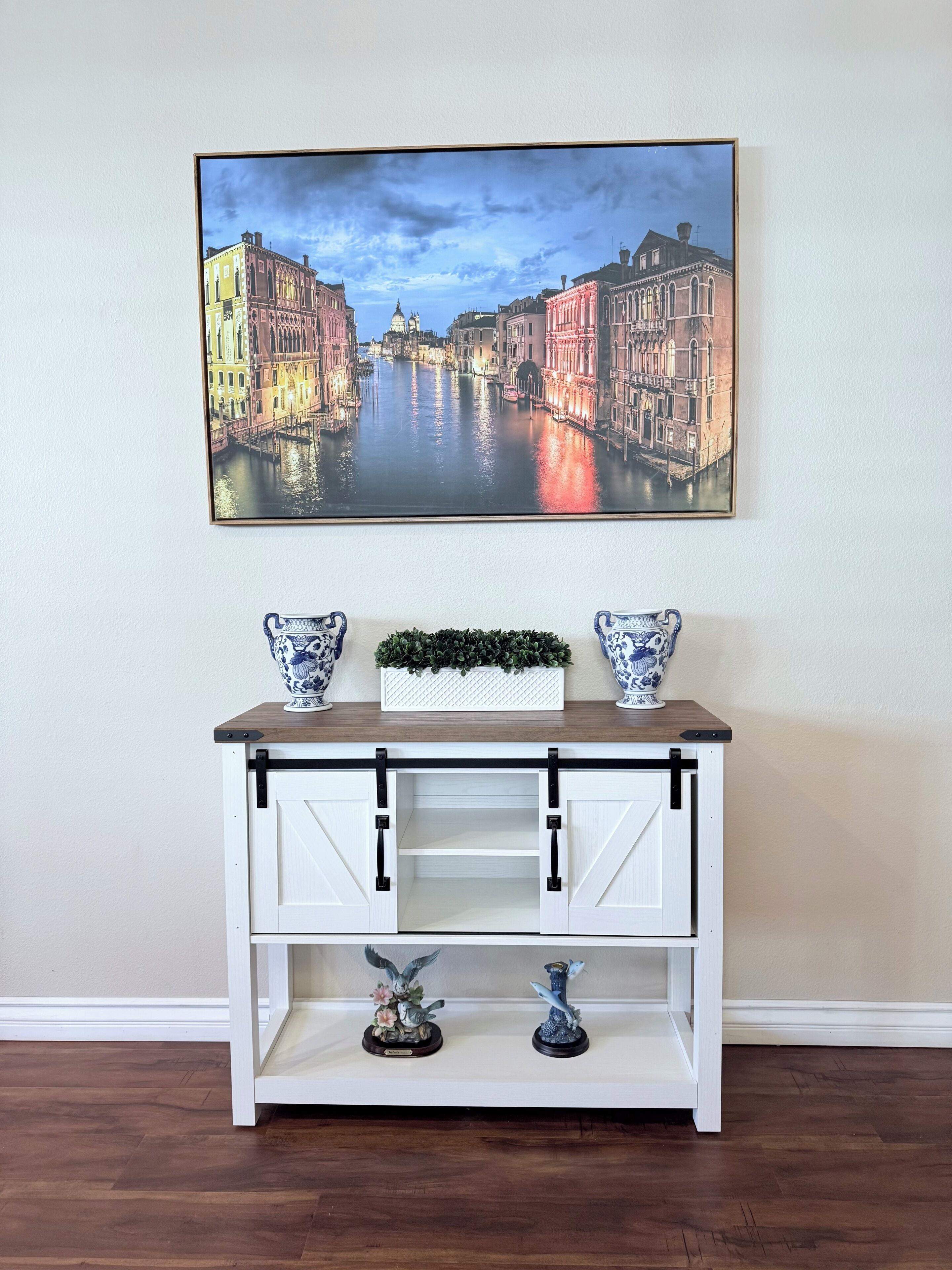 A white console table with two decorative vases, a small plant, and two figurines.