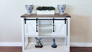 A white console table with two decorative vases, a small plant, and two figurines.