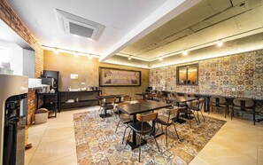 Ein Hotelkonferenzraum mit einem großen Tisch, Stühlen, einer Kaffeemaschine und einem an der Wand befestigten Fernseher.