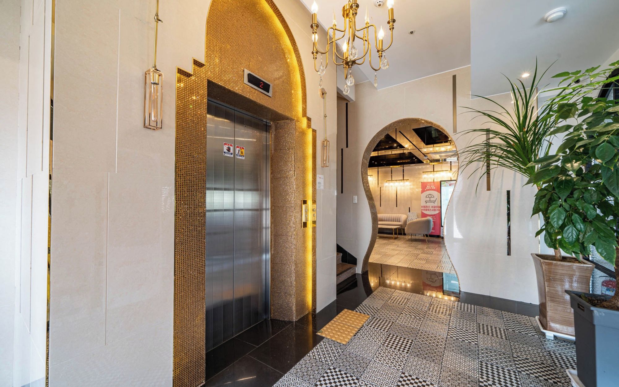 A hotel lobby with a modern design, including a reception desk, a waiting area, and a staircase leading to an upper floor.