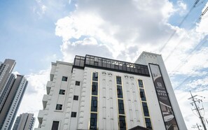 Un hôtel moderne, avec une façade en verre remarquable, de nombreuses fenêtres et une publicité bien visible annonçant son grand lancement.