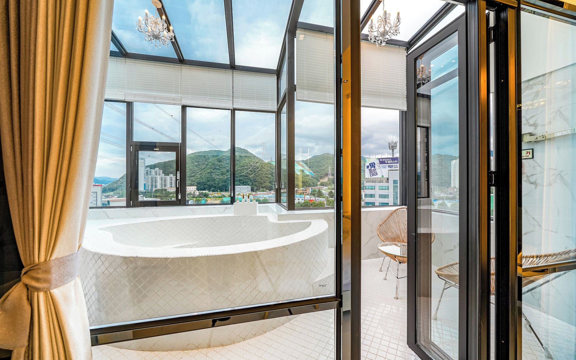 A modern interior with a large glass door leading to a balcony with a view of a mountainous landscape.