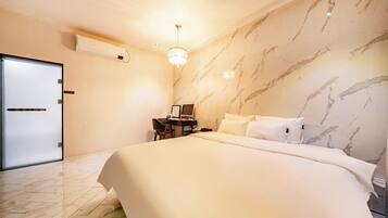 Una habitación de hotel con una cama, un escritorio, una silla, una computadora y un candelabro.