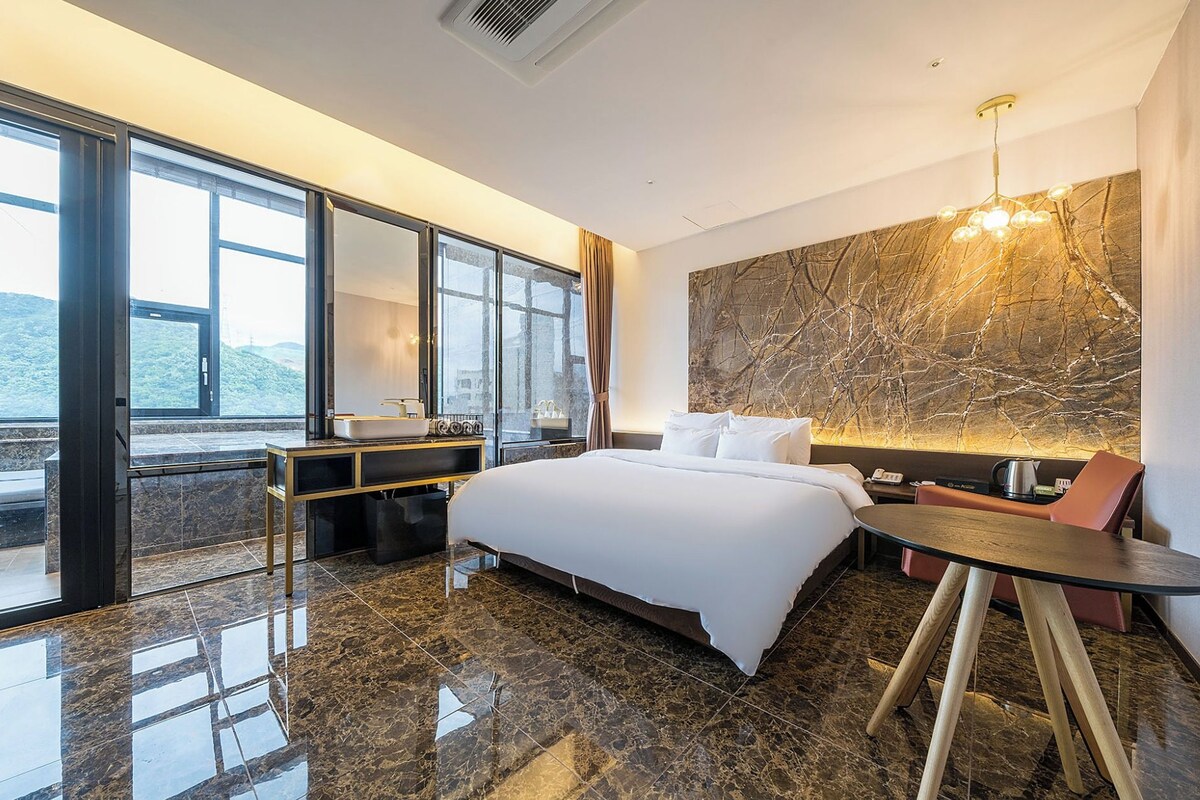 Une chambre d’hôtel avec un lit, une table de chevet et une vue sur l’extérieur.