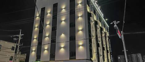 Un edificio de varios pisos con ventanas iluminadas y un letrero que dice 'Basta Restaurant' en la parte superior.
