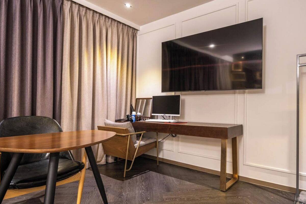 Een hotelkamer met een bureau, stoel, televisie en gordijnen.