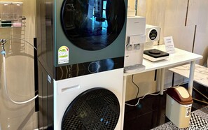 Ein moderner Waschraum mit einer Waschmaschine mit Frontlader, einem Trockner und einer Kaffeemaschine auf einem Tisch.