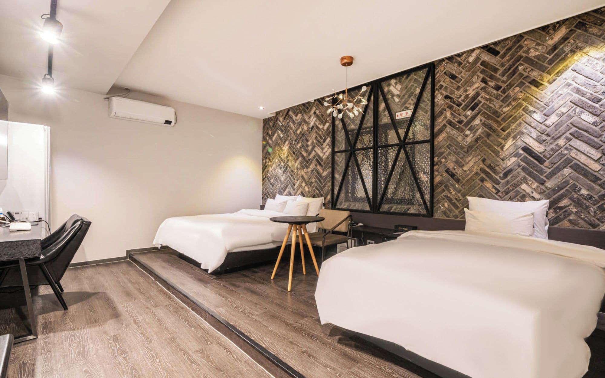 Une chambre d’hôtel avec deux lits, un bureau, une chaise et un mur orné d’un motif en chevrons.
