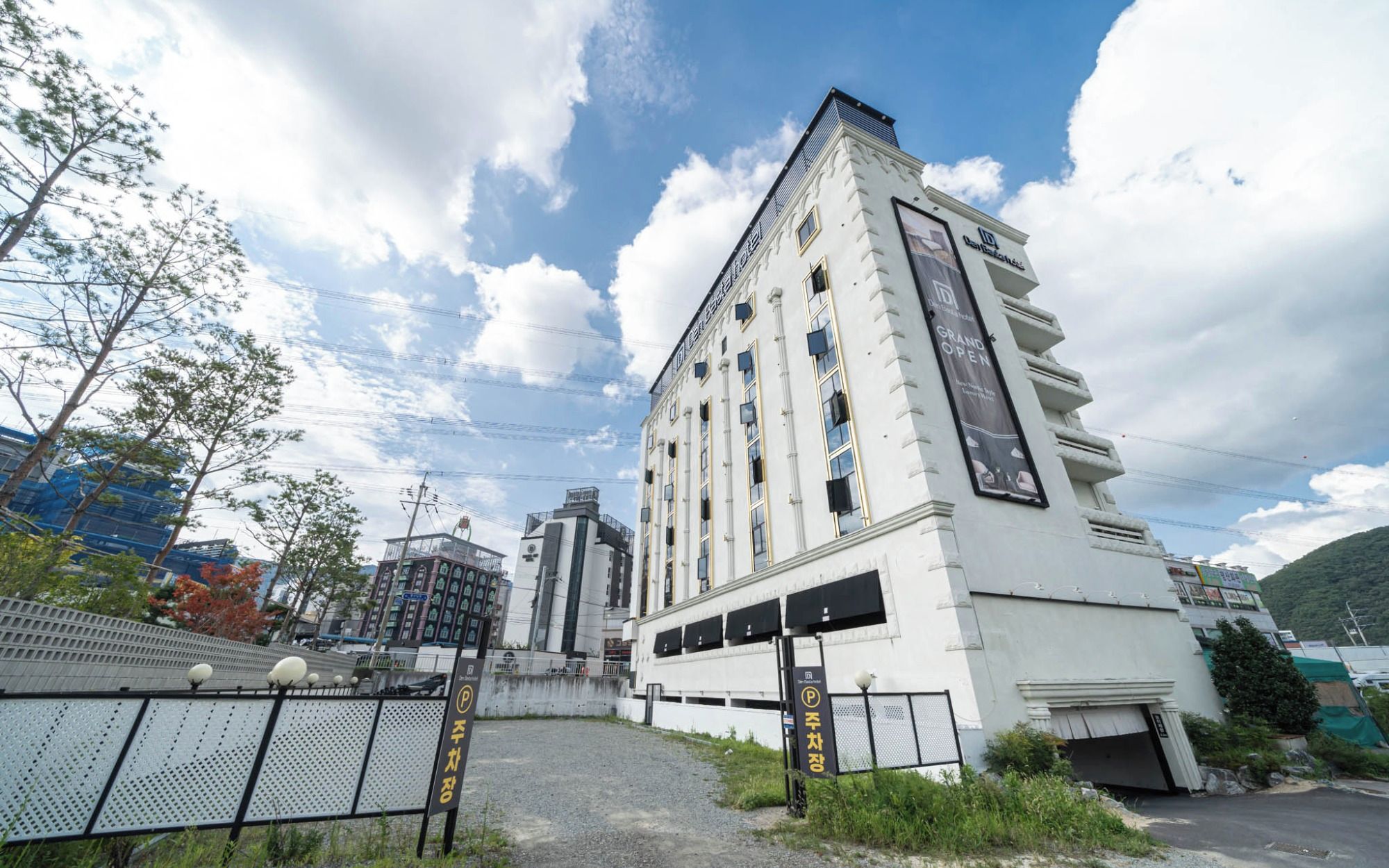 A white building with multiple floors, a gated entrance, and a sign indicating a parking area.