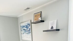 Una sala de estar con un sofá seccional gris, un cuadro enmarcado y dos estanterías con adornos.