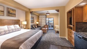 Une chambre d’hôtel avec un grand lit, un bureau, une chaise, une télévision et une kitchenette.