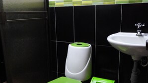 A bathroom with a toilet, a green trash bin, and a sink.