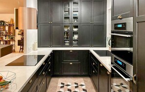 A modern kitchen with dark cabinetry, a built-in oven, and a countertop with a geometric tile backsplash. - Lovely home in Apeldoorn with WiFi (Apeldoorn)