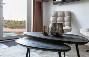 A modern living room with a round table, two decorative vases, a tufted armchair, and a view through a large window. - 2 bedroom stunning home in Wenum-Wiesel (Wenum-Wiesel)
