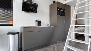 A compact kitchen with grey cabinets, a stainless steel trash bin, a coffee maker, and a TV mounted above the counter. - 2 bedroom stunning home in Wenum-Wiesel (Wenum-Wiesel)