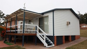 A two-story house with a covered patio, a staircase, and a brick foundation. - In Holiday Mode is a basic house in Manyana (Manyana)