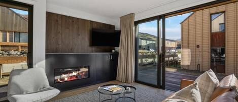 A modern living room with a fireplace, a flat-screen TV, and a large sliding glass door leading to an outdoor area.