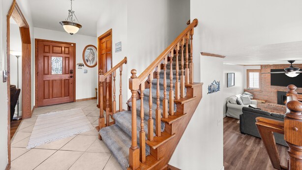 Un escalier avec des balustrades en bois et une main courante, menant à un espace de vie doté d’une cheminée et d’un canapé.