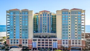 Un hotel de varios pisos con un atrio central, balcones y vistas a la playa.