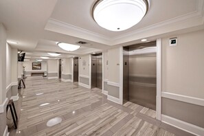 A hotel corridor with polished marble floors, modern lighting, and elevators. - 1502 True North 3 BR 3 BA Ocean View Condo (North Myrtle Beach)